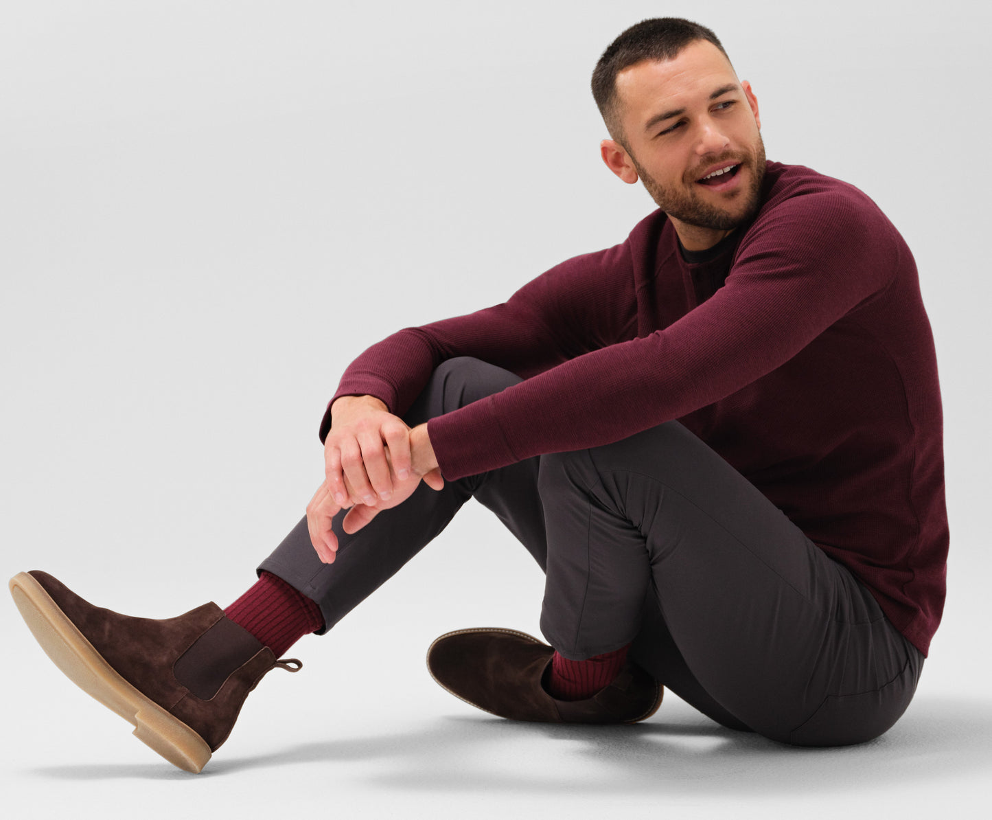 Sitting down view of a man wearing WARMKNIT Waffle Henley in Lambrusco Heather